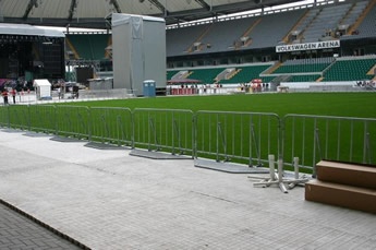 A row of vertical police barriers are installed surrounding at the football ground.